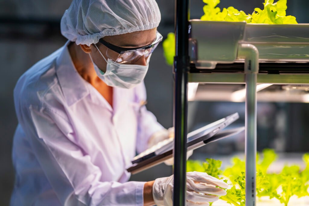 a scientist in a mask, hairnet, and gloves records observations a scientist in a mask, hairnet, and gloves records observations
